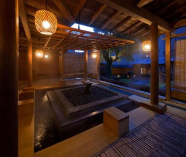 Evening wooden onsen area with lanterns and central bath at Furuyu Onsen Oncri in Saga, Kyūshū