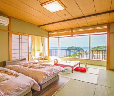 Tatami room with futon bedding, shoji screens and balcony overlooking green hills at Futagojimasou Wakayama