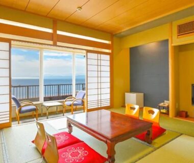 Tatami room with low table shoji screens and balcony overlooking the sea at Futagojimasou Wakayama