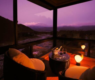 Covered terrace with two lounge chairs, low table, wooden soaking tub and distant mountain view