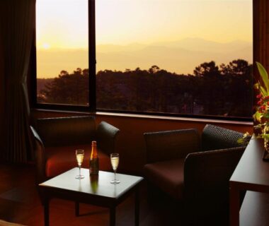 Low table and two chairs with drinks facing sunset over forested mountains at Futari Shizuka, Chūbu Japan