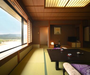 Tatami room with low table, cushions and large window overlooking valley at Futari Shizuka in Nagano