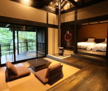 Tatami room with low table, sleeping alcove and balcony overlooking greenery at Gekkoju Kurokawa, Kumamoto
