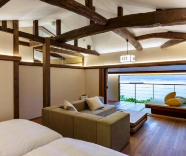 Twin beds and sofa under exposed wooden beams, large window overlooking water, Genmyoan, Kyoto, Kansai, Japan