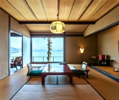 Tatami room with low table, floor cushions, wooden ceiling and balcony with sea view at Genmyoan Kyoto