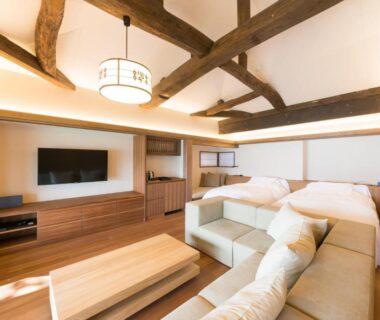Spacious room with exposed wooden beams, low table and sofa at Genmyoan in Kyoto, Kansai