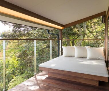Wooden terrace with cushioned daybed, glass railing and treetop views at Genmyoan in Kyoto, Kansai, Japan