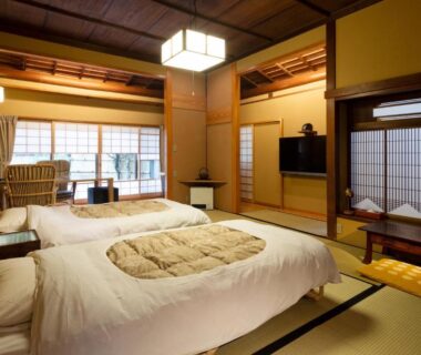 Traditional tatami room with futon bedding, shoji screens and low table at Gensen Uenoya in Kanagawa