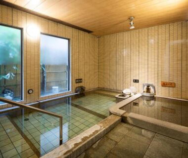 Tiled indoor onsen baths with wooden ceiling and handrails at Gensen Uenoya in Kanagawa, Kantō