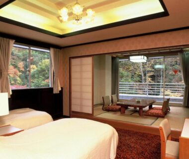 Twin beds, tatami seating area, shoji screens and balcony with forest view at Gensenkan in Tochigi, Kantō