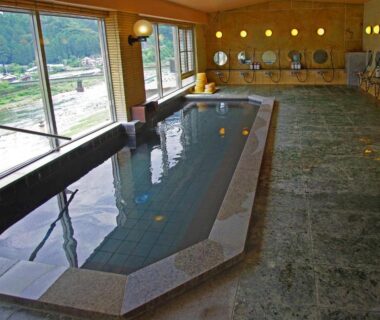 Indoor communal onsen with large windows overlooking scenic outdoors at Gero Onsen Yukyunohana Gifu Chūbu