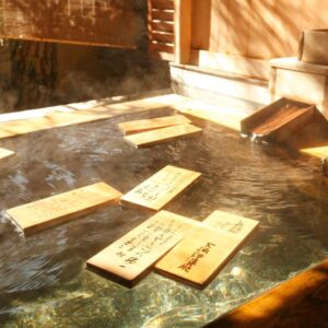 Steaming wooden onsen with floating wooden plaques at Gingetsu ryokan, Nagano, Chūbu