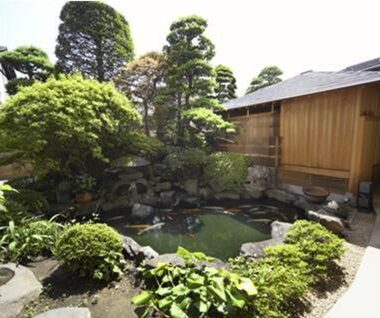 Stone-lined pond with surrounding trees and wooden building at Gingetsu, Nagano, Chubu