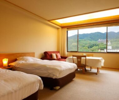 Carpeted twin room with lamps and large window framing green mountains at Ginsuisou Choraku, Hyōgo, Kansai