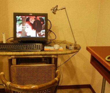 Rattan chair and compact desk with monitor, keyboard, and lamp in Gion Fukuzumi Kyoto room interior