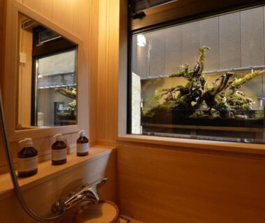 Compact wooden bathing room with hand shower, stools and window overlooking small garden display at Gion Oyado Kikutani Kyoto