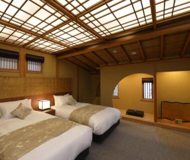 Twin beds in a traditional tatami room with wooden lattice ceiling and tokonoma alcove at a Kyoto ryokan