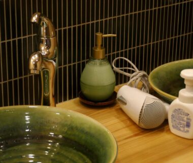 Green ceramic sink with chrome faucet, soap dispensers and hair dryer on wooden counter at Gion Ryokan Q-beh Kyoto