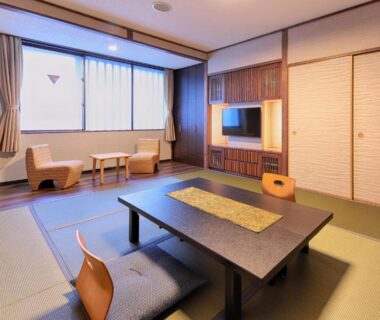 Tatami room with low table, zabuton chairs, shoji screens and window at Gion Shinmonso in Kyoto