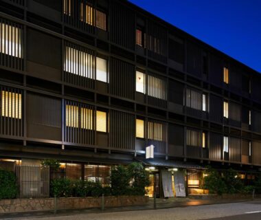 Night view of lit wooden facade and entrance at Gion Shinmonso in Kyoto