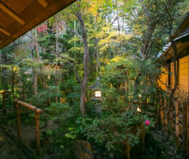 Lush enclosed garden with stone lanterns beside shoji rooms at Gion Yoshiima in Kyoto