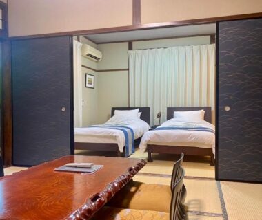 Tatami room with low table and two beds at Good Stay Mizuho in Ōita, Kyūshū