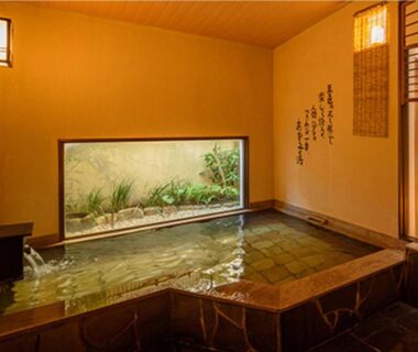 Warm tiled indoor onsen with garden window at Good Stay Mizuho in Oita, Kyushu