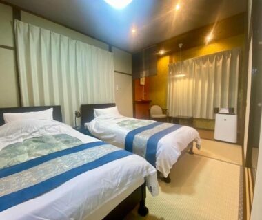 Two single beds on tatami flooring with sliding screens and warm lighting at Good Stay Mizuho, Ōita