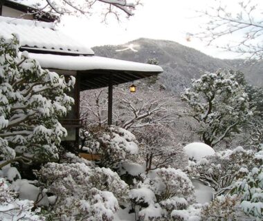 Snow-covered garden and wooden veranda overlooking forested hills at Gora Kansuiro in Kanagawa