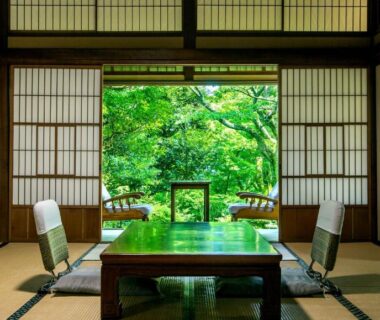 Traditional tatami room with low table, shoji screens and a lush green garden visible through sliding doors