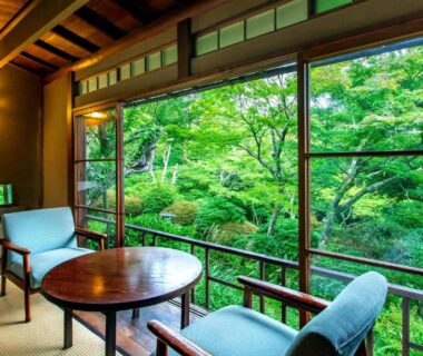Tatami room with low table and chairs overlooking leafy garden at Gora Kansuiro in Kanagawa Kantō