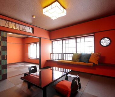 Traditional tatami room with low table, floor cushions, shoji windows and warm red walls