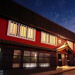 Red traditional ryokan exterior with wooden lattice and lit windows at dusk, Goyokan, Shizuoka Chubu Japan
