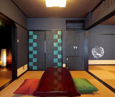 Tatami room with low wooden table, zabuton cushions, sliding doors and wall art at Goyokan in Shizuoka Chūbu