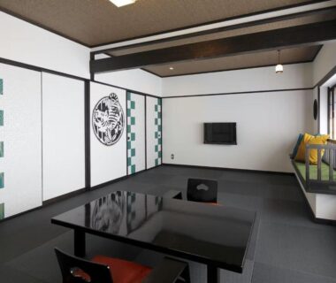Traditional tatami room with low lacquer table, shoji screens, bench seating and wall-mounted TV at Goyokan Shizuoka