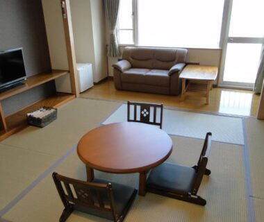 Tatami room with round low table, floor chairs and sofa at Granvillage Toya Daiwa Ryokan Annex in Hokkaidō