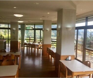Dining room with wooden tables and chairs, floor-to-ceiling windows and mountain views at Green Spa Tsutsuga, Hiroshima