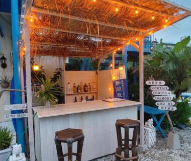 Outdoor bar counter with stools, string lights and tropical plants at Guest House Churaumi in Chūbu, Shizuoka