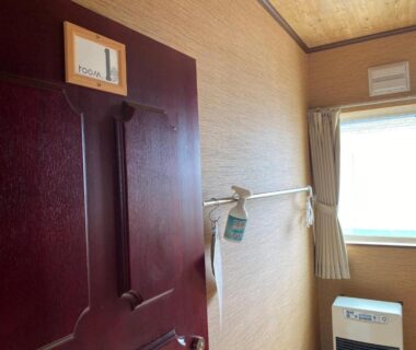 Wooden door, towel rack and curtained window at Guest House Nemuroman in Hokkaidō, Japan