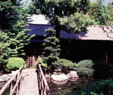 Wooden footbridge over a pond leading to a traditional building at Gyokutei in Kanagawa, Kantō, Japan