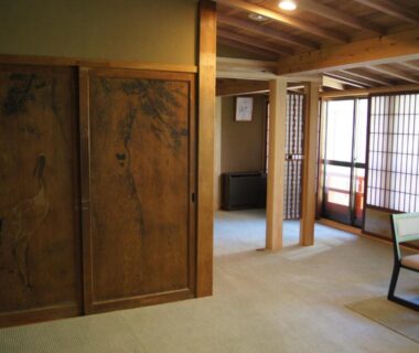 Spacious tatami seating area with shoji screens, wooden beams and carved sliding doors at Gyokuzoin in Nara