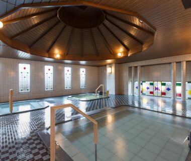 Tiled indoor onsen with wooden dome ceiling and stained glass windows at HAKODATE Uminokaze, Hokkaidō Japan