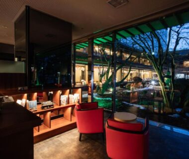 Lounge seating with floor-to-ceiling glass overlooking a lit courtyard at HAKODATE Uminokaze Hokkaidō