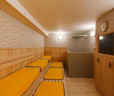 Wood-paneled relaxation room with tiered benches and yellow cushions at HAKODATE Uminokaze Hokkaidō