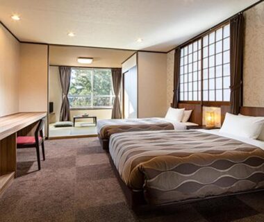 Two beds with shoji screens and low seating by balcony at HESTA Hakone Guest House, Kanagawa, Japan