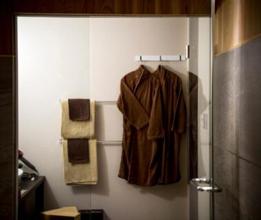Brown bathrobes and folded towels hanging in a ryokan bathroom at HOSHINO-OTO Kyoto