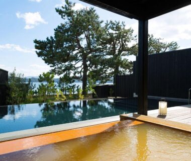 Wooden onsen bath and infinity pool overlooking trees at HOSHINO-OTO in Kyoto, Kansai