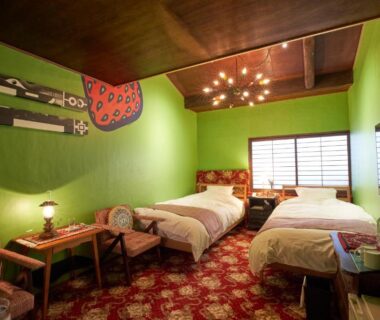 Twin beds, shoji screens, wooden ceiling and low seating in a green-walled room at HOTEL Clam Chowder, Kyoto