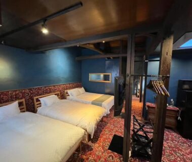 Two twin beds, wooden beams, blue walls and patterned carpet at HOTEL Clam Chowder, Kyoto
