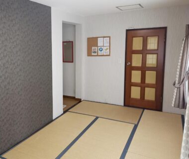 Tatami-floored room with wooden paneled door and curtained window at HOTEL HOUSE LEE Tokyo